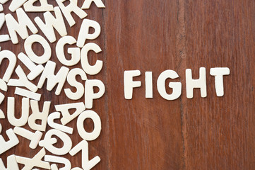 Word fight  made with block wooden letters next to a pile of other letters over the wooden board surface composition