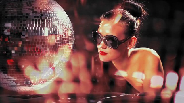 a sexy woman dances with a discoball