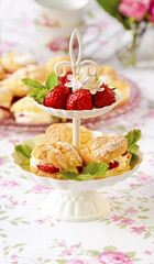 Cream puffs cakes or profiterole filled with whipped cream served with strawberries in plateau