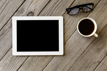 White tablet with blank screen on wooden table