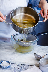 Person making chicken broth stock soup in caserole. Slow cooking food concept.