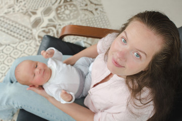 Obraz na płótnie Canvas Young mother newborn her lap armchair top view