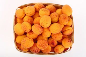 Fresh ripe apricots in wooden basket over white