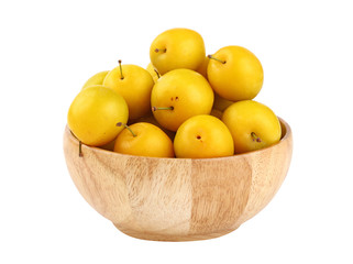 Fresh yellow plums in wooden bowl over white