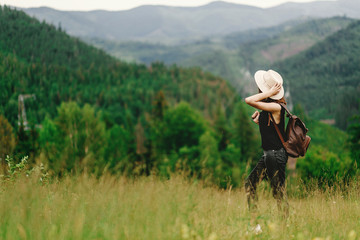 stylish hipster woman with backpack looking at  amazing woods an