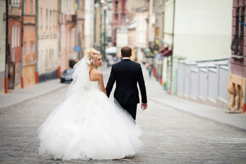Funny bride looks over her shoulde waling with a groom in black