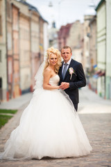 Naklejka premium Rich wedding couple stands on the street holding each other hand