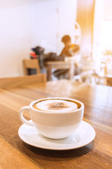 White cup of coffee with smoke on table in cafe.