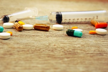 drugs pills and a syringe on wooden table, medicine background in vintage tone with copy space,...