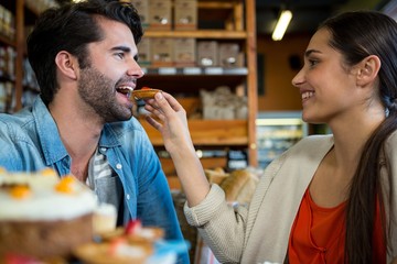 Happy woman feeding man with dessert