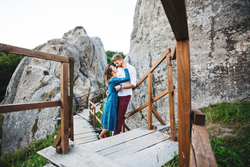 Obraz na płótnie Canvas Embracing couple on wooden bridge between rocks