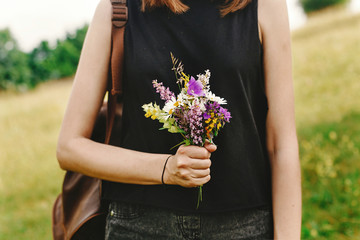 stylish hipster woman with backpack gathering and holding  wildf