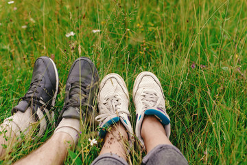 stylish hipster couple legs on sunny grass in meadow  in summer
