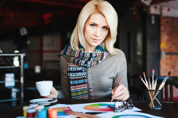 Fototapeta premium Girl sitting in cafe with cup of coffee and drawing