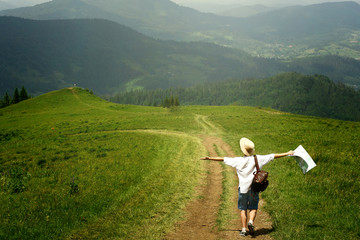 man traveler holding map and walking to top of sunny hill on bac