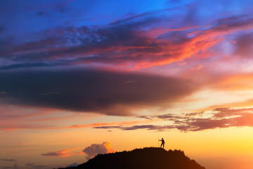 At the top of the world. A person is standing on the hill beneath colorful sky at the sunset. Clicked on the top of Batur volcano (Bali, Indonesia). - 117805231