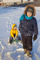 Fototapeta na wymiar Happy Boy pulling sled with his friend on snowy road