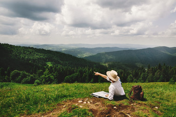 stylish hipster traveler sitting at top of mountains with amazin