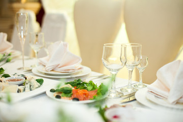 Red fish with black olives lie on the plate between empty plates