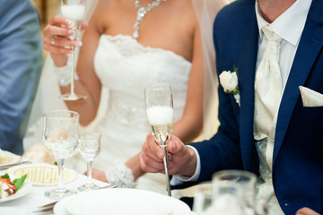 Stylish bride and groom hold in their hands steel champagne flut