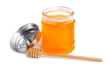 Honey jar and wooden dipper on white background