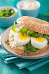 breakfast sandwich on bagel with egg cream cheese arugula