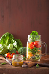 healthy vegetable salad in mason jar. tomato broccoli carrot pea