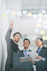 Businessman pointing at stickers with business ideas on glass wall