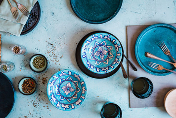 Empty dinning indigo and decorative green bowls over turquoise stone table.