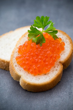 Bread with fresh cream cheese and red caviar on table.