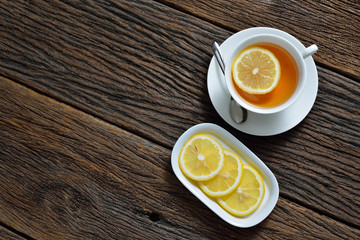 Top view of cup of tea with lemon on wooden table