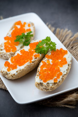 Red caviar on bread on white plate.
