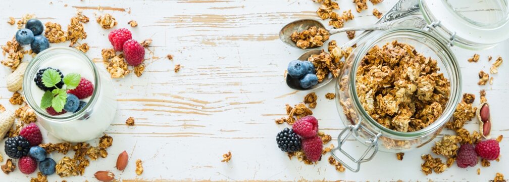Granola with berries on white wood background