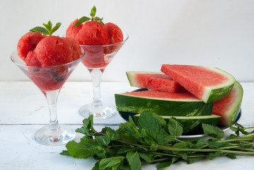 Watermelon balls in glass with mint and star of watermelon on a wooden table