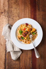 Pasta with seafood and vegetables on a plate on a wooden background, top view