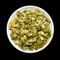 Pumpkin seeds in a plate, black background