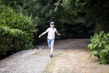 Fototapeta na wymiar Beautiful boy running on a path in a summer park. Selective soft focus. Shallow depth of field