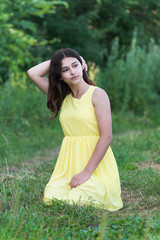 Naklejka na ściany i meble The girl in yellow dress sitting on grass