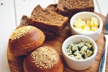 Green and butter with French baguette and black bread on a wooden Board