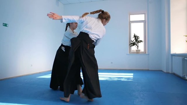 Two girls in black hakama practice Aikido on martial arts training. Slow motion