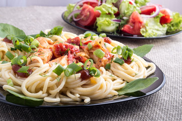 Home-cooked meals on a gray mat - spaghetti and vegetable salad