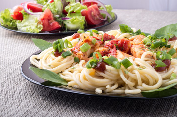 Home-cooked meals on a gray mat - pasta and vegetable salad