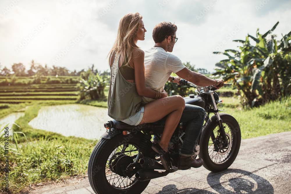 Wall mural man riding motorcycle with a woman on rural road