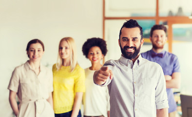 Obraz premium happy man pointing finger at you over office team