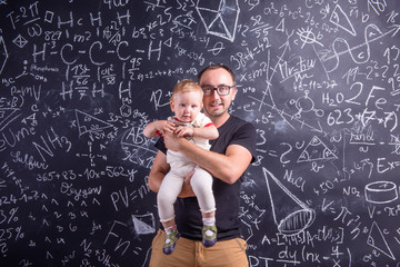 Young father with little daughter against big blackboard