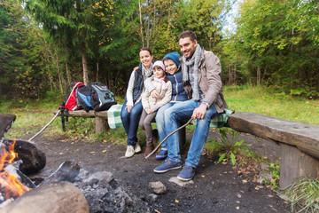 happy family sitting on bench at camp fire