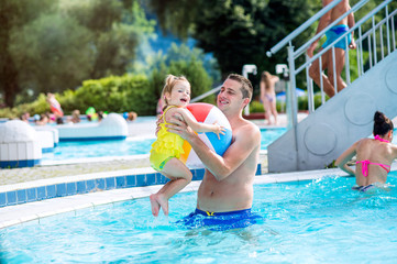 Fototapeta na wymiar Father with his daughter in swimming pool. Sunny summer.