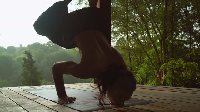 Yogi man bare-chested doing handstand outdoors.