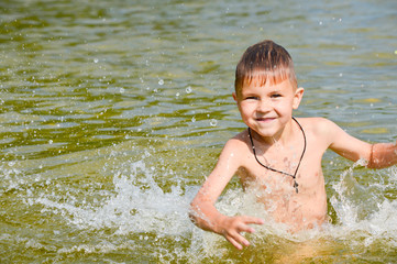 Boy swims in the lake water with a green tint.