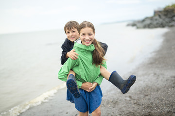 boy and girl having fun on rain close to a sea